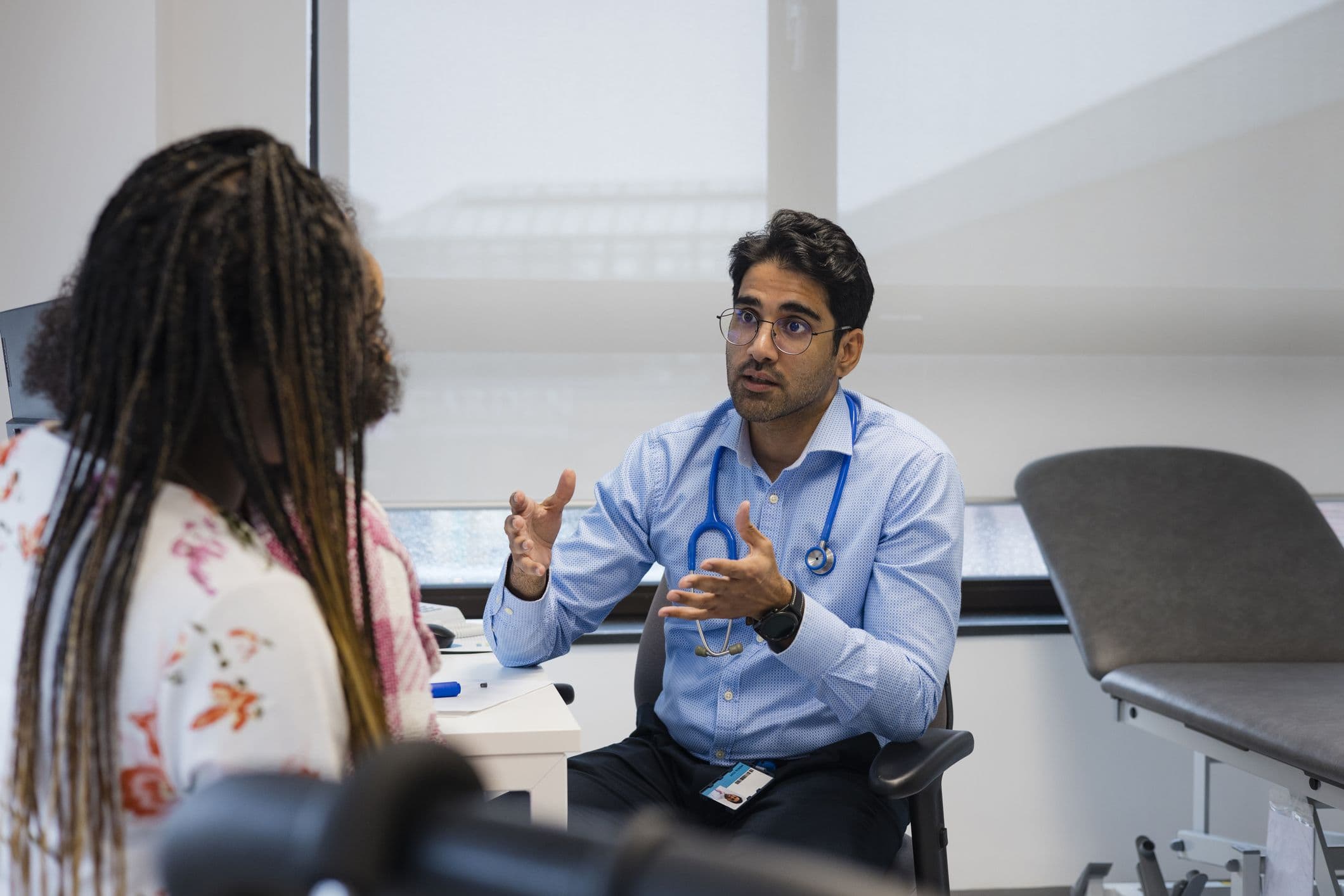 GP with a seated patient in an exam room.