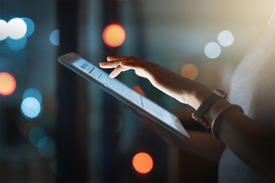 Side view of woman's hand tapping on a tablet device