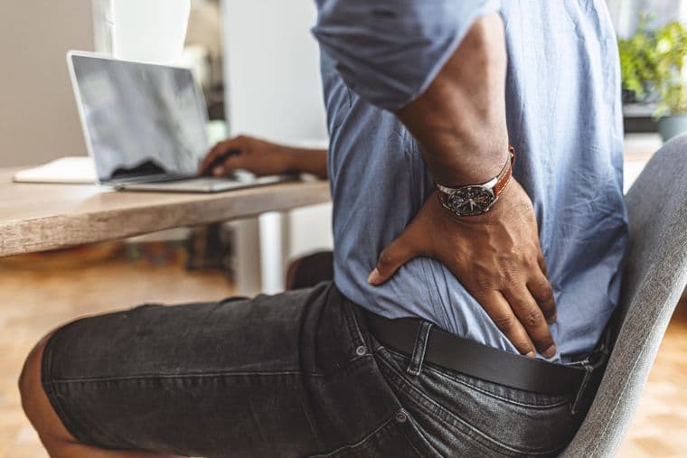 A man sitting at a desk experiencing kidney pain