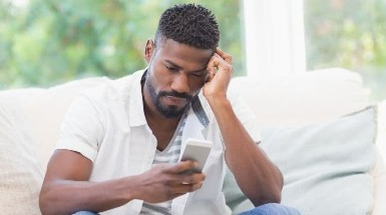 Man sat on sofa looking at mobile phone