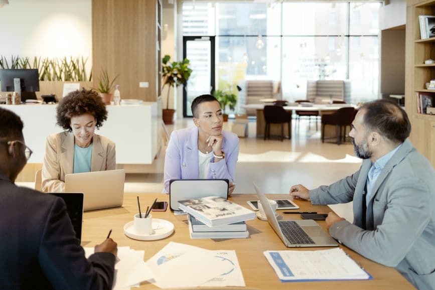 Diverse group of adults, in discussion around a table